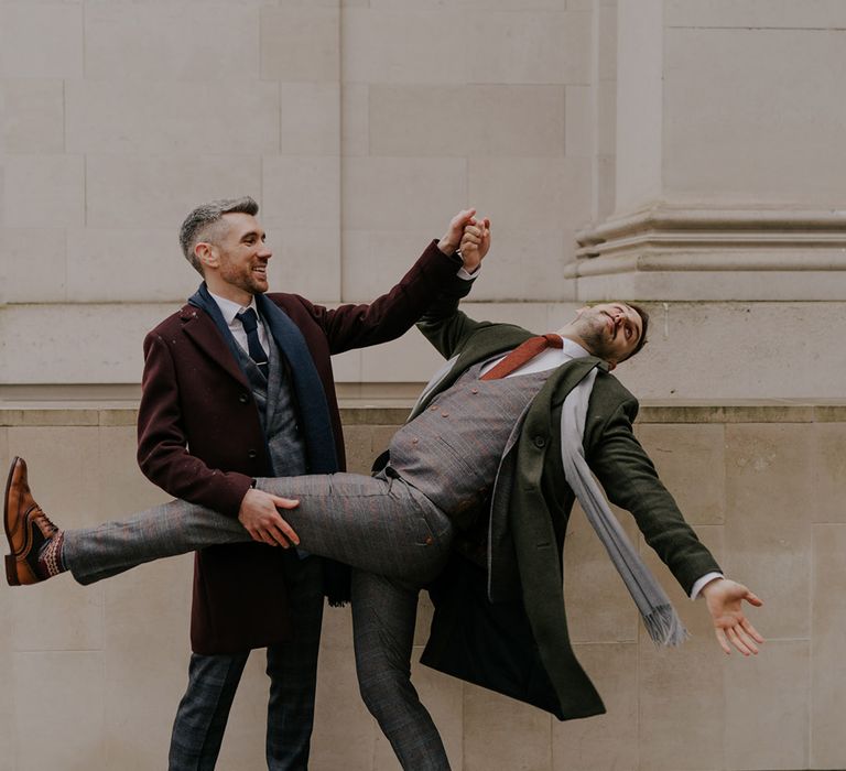 Groom leans back as groom holds him in silly post-wedding photo in London