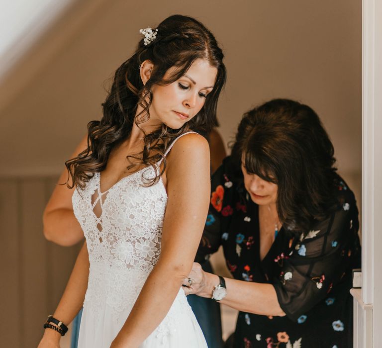 Bride looks behind her as her wedding dress is done up on her wedding day