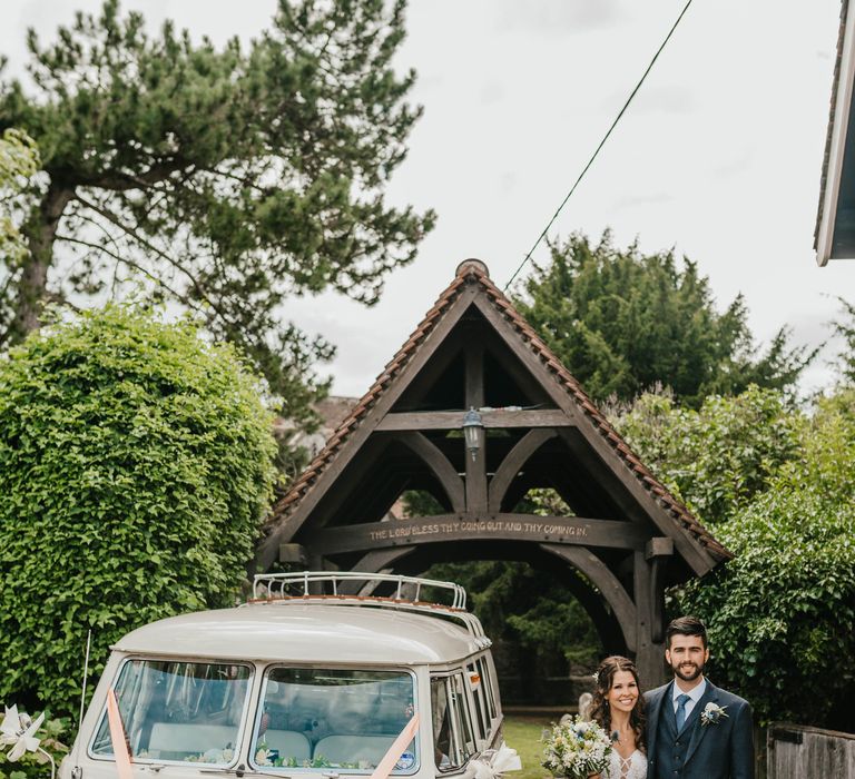 Bride & groom stand beside vintage VW camper van in white