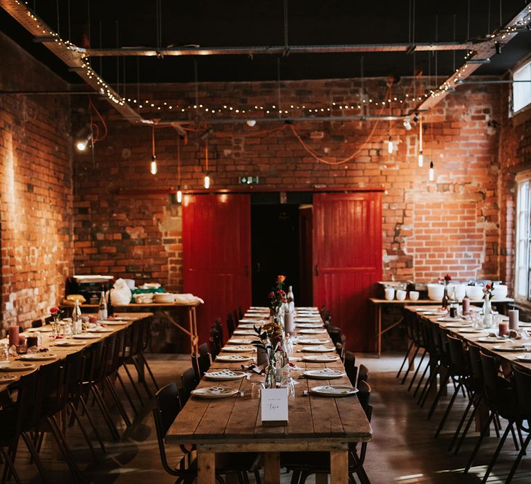 Long wooden trestle tables are laid out for a wedding breakfast at an industrial wedding venue in Sheffield.