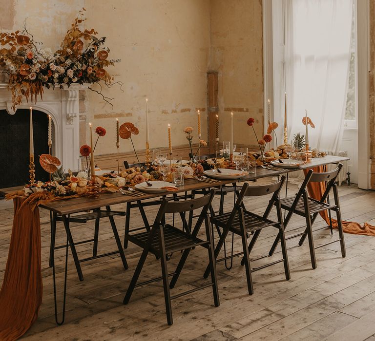 Intimate reception at Clerkenwell House in London with distressed walls, hanging chandelier and original fireplace decorated in brown autumn wedding flowers 