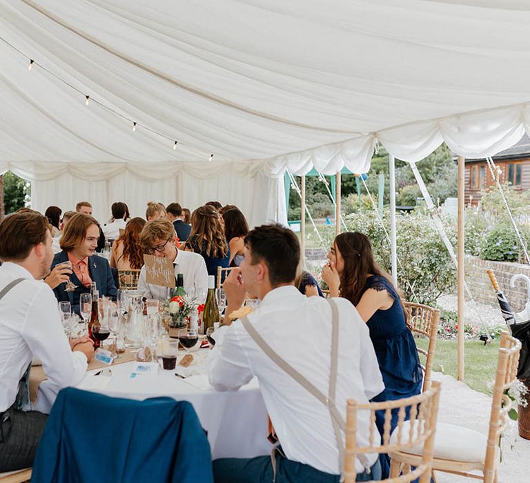 Wedding guests gather in marquee for reception 