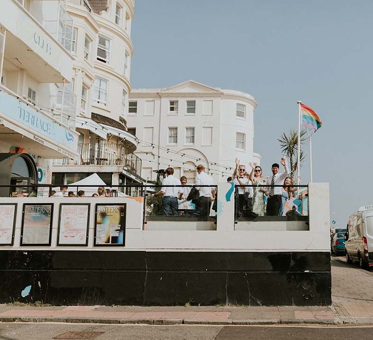 Wedding guests wave from balcony 