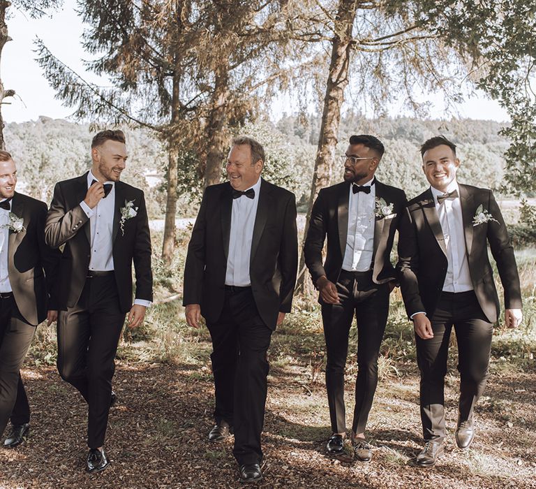 Groom walks with his groomsmen who all wear black tie on wedding day