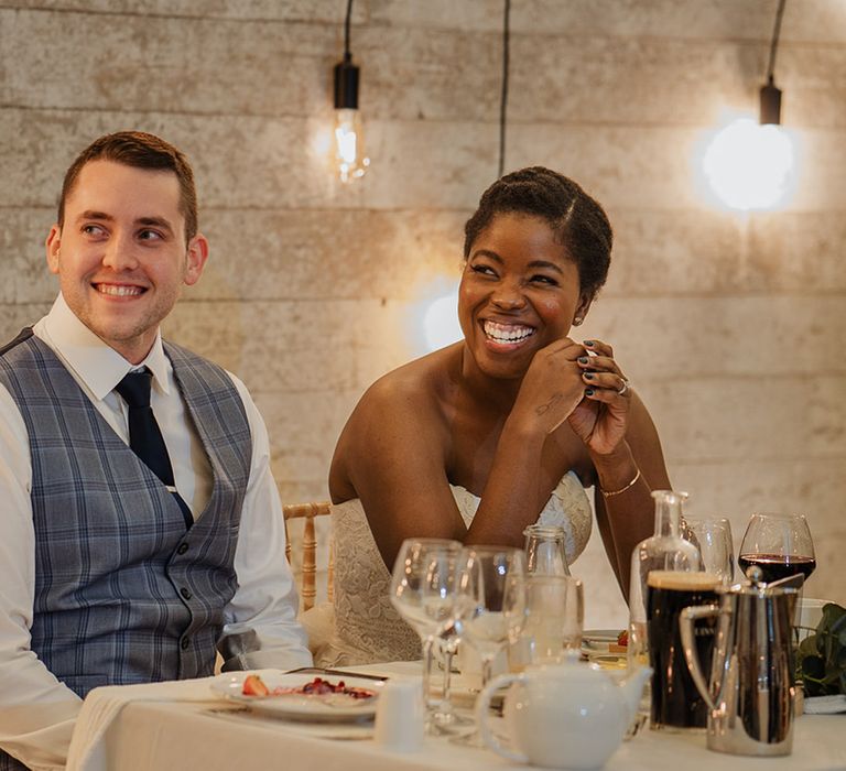 Happy Groom smiles in his checked waistcoat along side his bride at wedding reception 