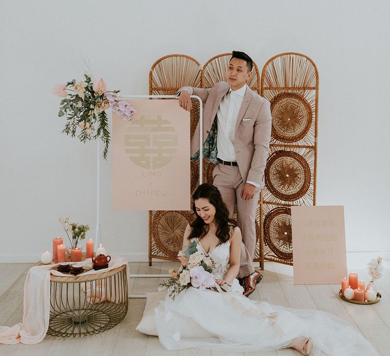 Bride smiling holding pink and white bouquet with groom surrounded by asian inspired wedding decor 