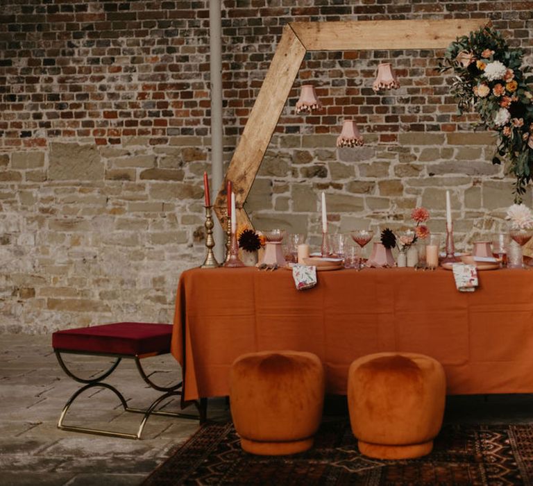 Wedding table decor with pink lampshades, candles, flowers and a wooden hexagon frame backdrop 