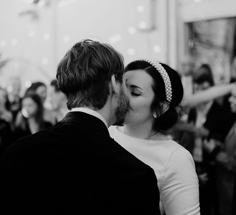 Bride in trendy pearl headband wedding as she kisses the groom