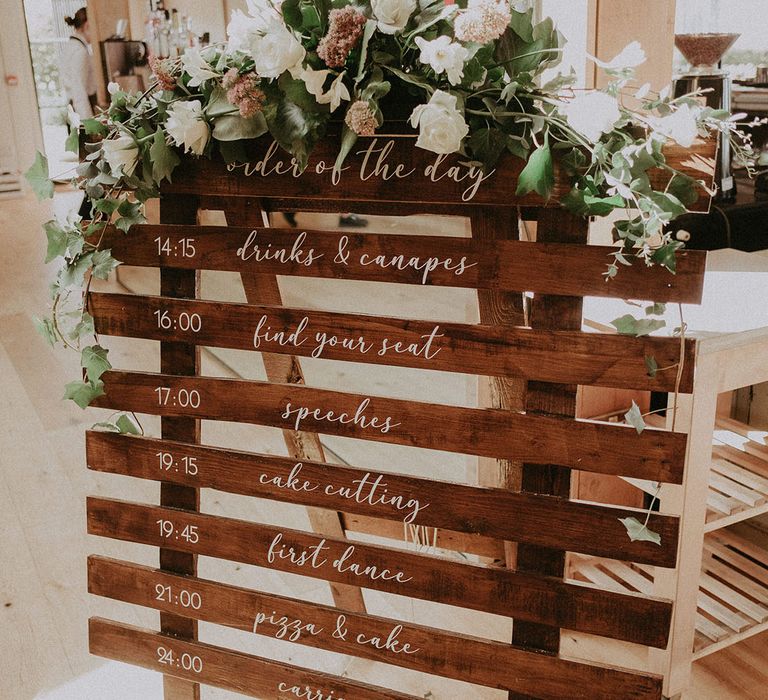 DIY wooden crate order of the day sign with cursive white font and pretty flower decoration