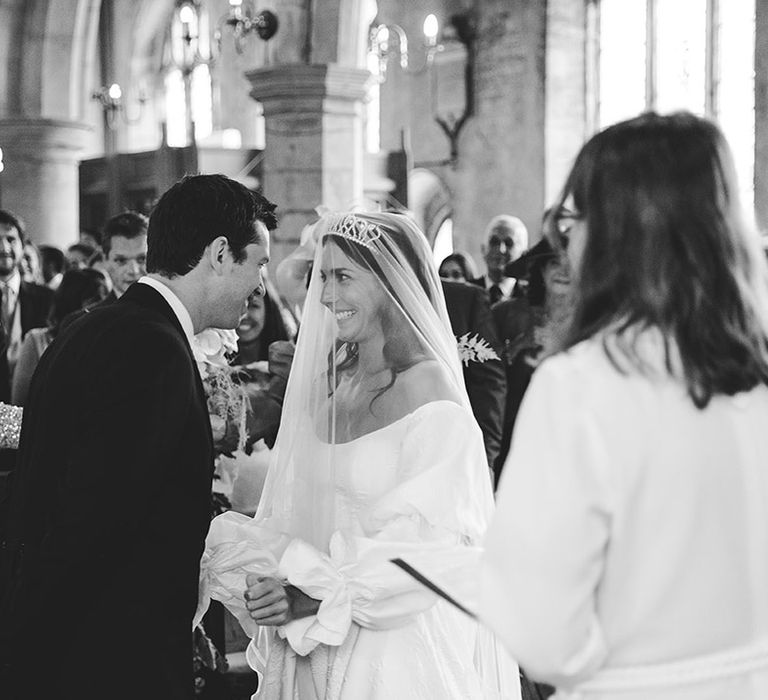 Bride and groom look into each other's eyes and smile at the altar for church wedding ceremony 