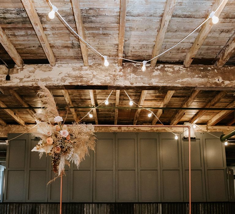 Copper archway with dried and fresh flower autumnal toned displays for industrial wedding with candles 