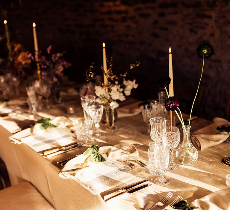 Crystal glassware with white candles and gold candleholders with red flowers and green velvet bow decor 