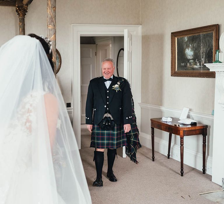 Father of the bride in black tie with kilt gets first look at the bride 