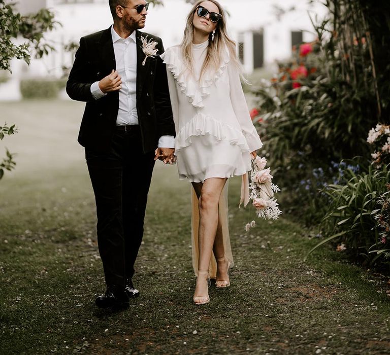 Bride in a short wedding dress and sunglasses and groom in a black suit at Waresley Park Estate wedding 