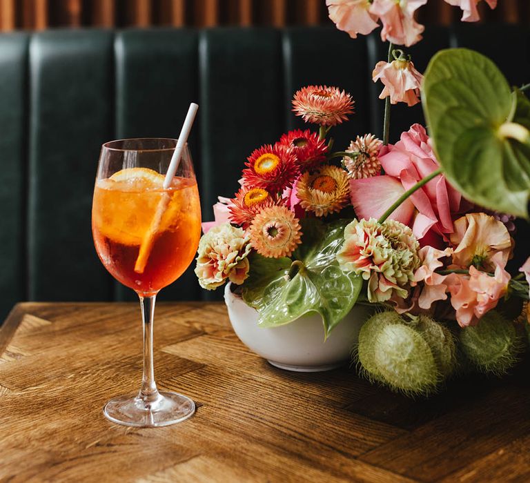 Aperol Spritz wedding drink on wooden table at Singer Tavern with pink, green and white wedding flower arrangement 