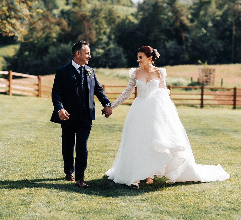 Bride and groom walk around the gardens of their wedding venue together 