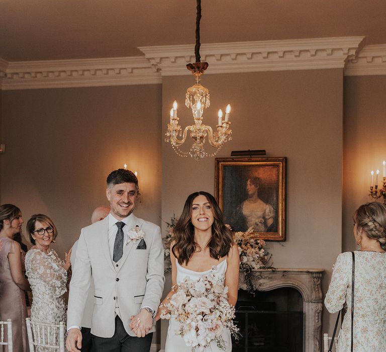 Smiling bride and groom exit their intimate wedding ceremony at Iscoyd Park venue 