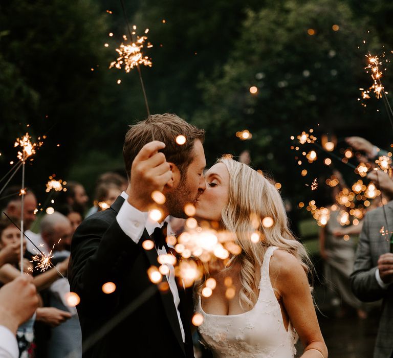 The bride and groom share a kiss as they have a sparkler send off 