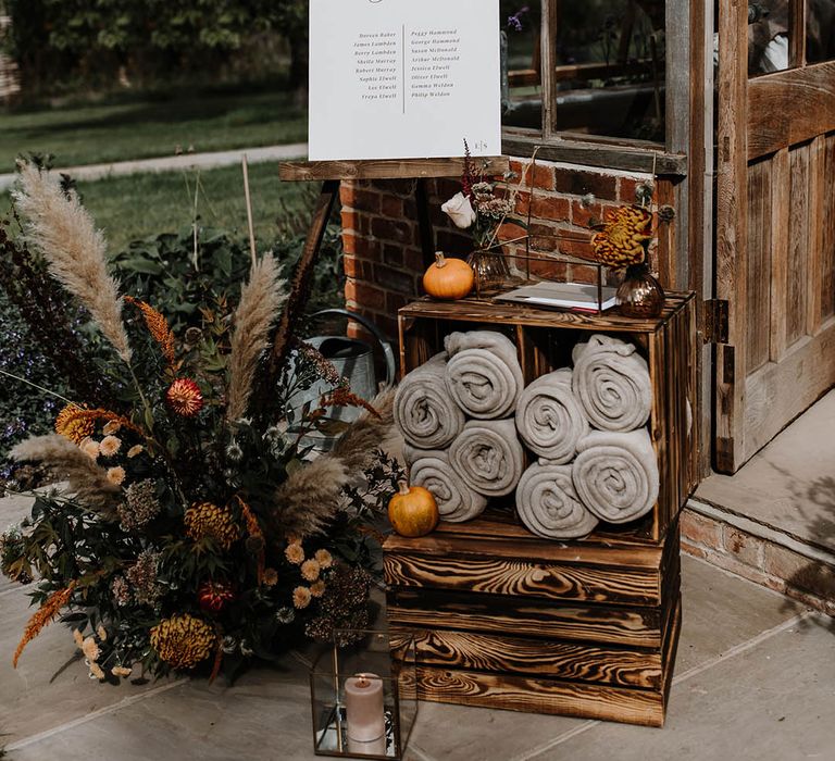 Simple table plan with a wooden crate full of grey blankets for the chilly autumnal wedding 