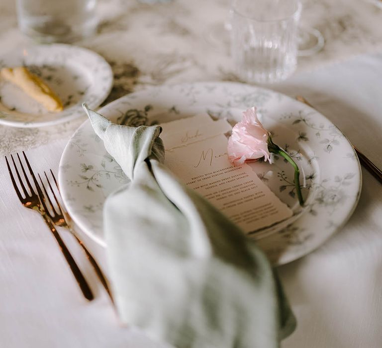 Beautiful place setting with sage napkin, menu and floral patterned plates