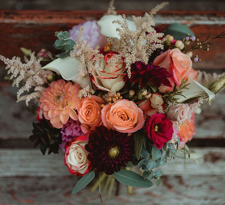 Colourful orange, pink, and red wedding bouquet with roses and lilies for festival wedding 