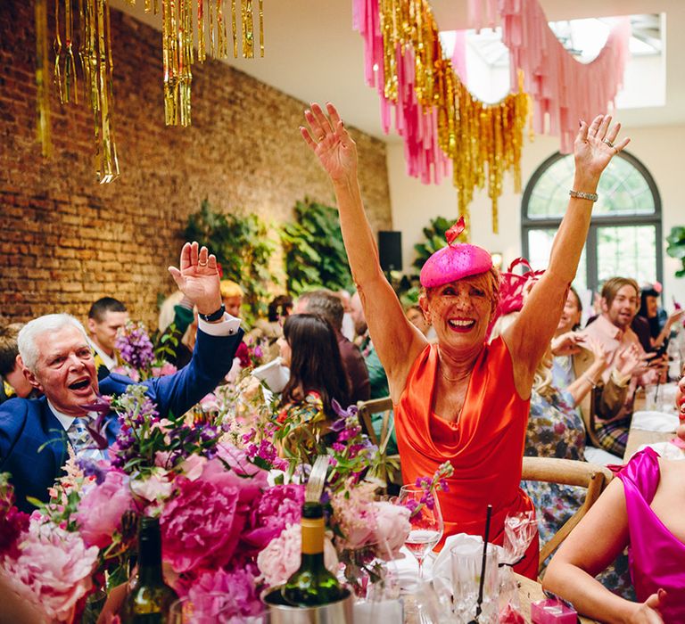 Wedding party standing up, dancing and singing at summer wedding at Middleton Lodge with gold, baby pink and light pink streamers and foliage decorations