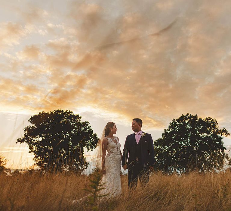 Win wedding photography from We Are // The Clarkes. This wedding photo shows golden hour featuring Bride and Groom walking through field