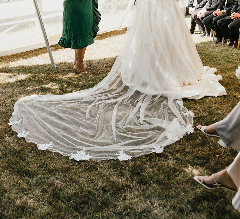 Bride wears floor-length drop veil complete with floral appliqué edge 