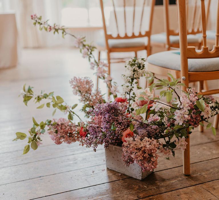 Bright floral arrangements line the aisle beside wooden chairs of Kew Gardens wedding 