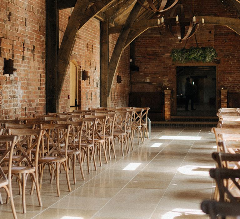 Rustic barn Grangefields wedding venue with chandelier with candles and wooden chairs 