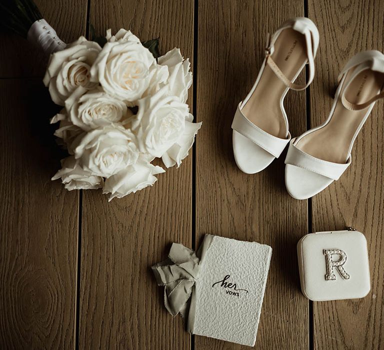 Round white rose bouquet with wedding vows, white shoes, and pearl personalised mini purse for the bride 