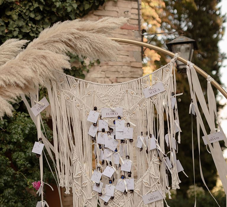 Macrame wedding decor hangs on circular golden arch complete with pampas grass arrangements 