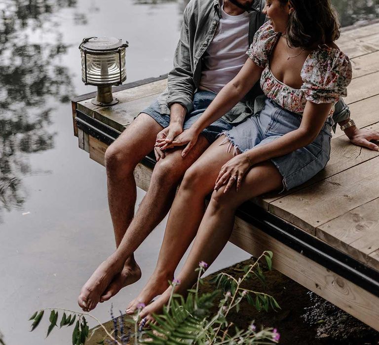 Bride and groom sitting at the end of the pier with their legs dangling over the water for Prezola wedding honeymoon, bride to be gift box 