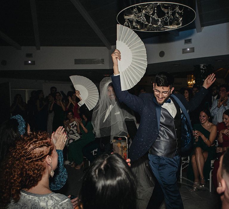 grooms in tuxedos dancing with fans at their evening receptions 