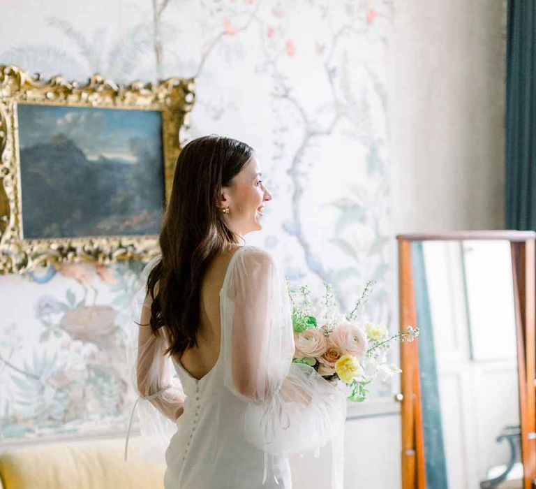 Bride in long sheer puff sleeve satin wedding dress with low back and button detailing 