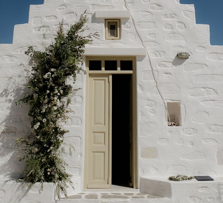 White wedding chapel in Paros, Greece at destination wedding with green and white flower arrangements