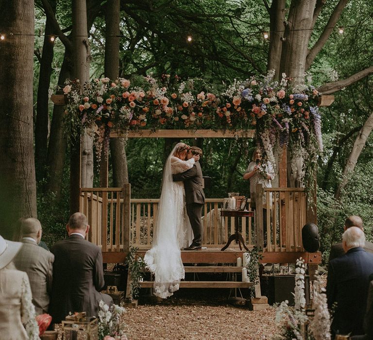 The bride and groom share their first kiss as a married couple at their outdoor humanist wedding ceremony in the woods