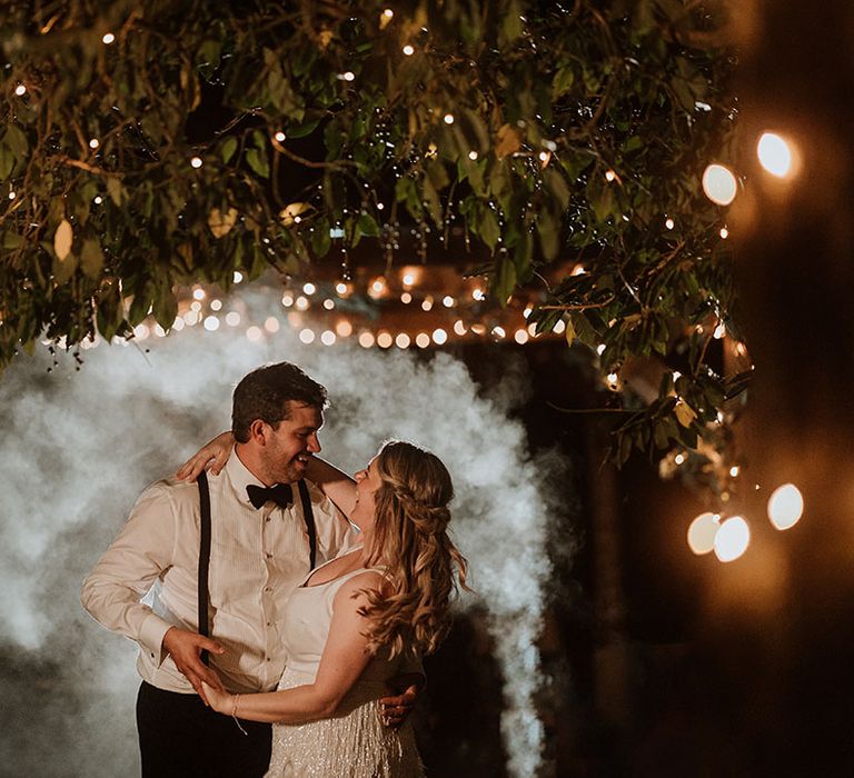 Bride in wedding reception outfit posing with groom for a cute couple photo 