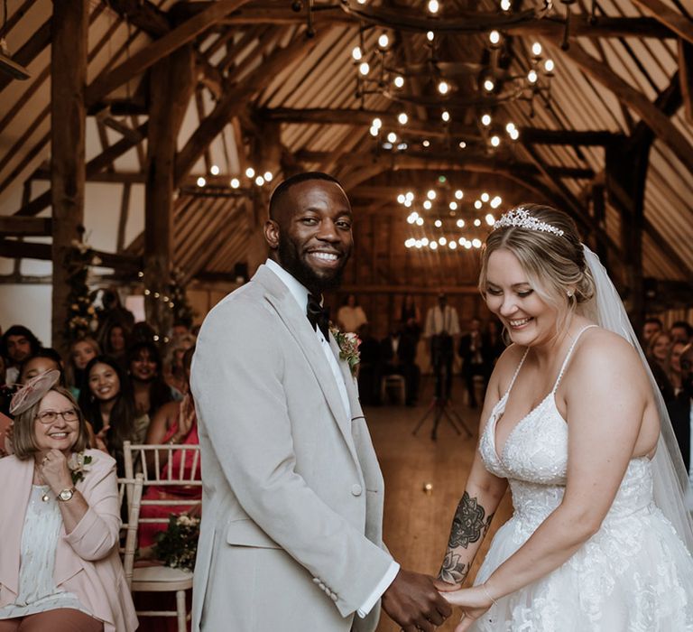 The groom in a velvet suit stands facing the bride holding hands for their wedding ceremony at Colville Hall