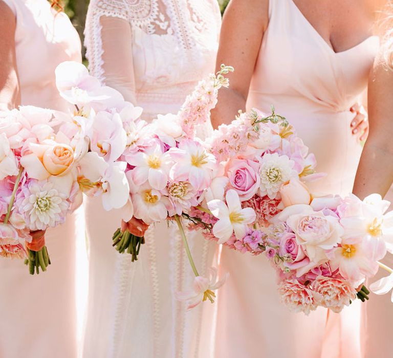 Bride and bridesmaids holding baby pink wedding bouquets with peonies, reflexed tulips, dahlias and more 