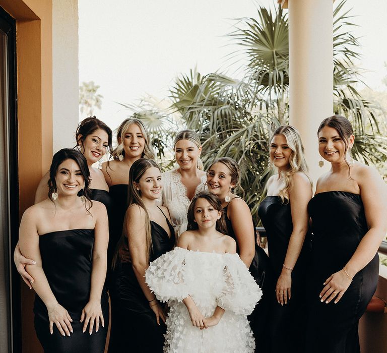 bridal party in satin black bridesmaid dresses and flower girl in butterfly appliqué white dress