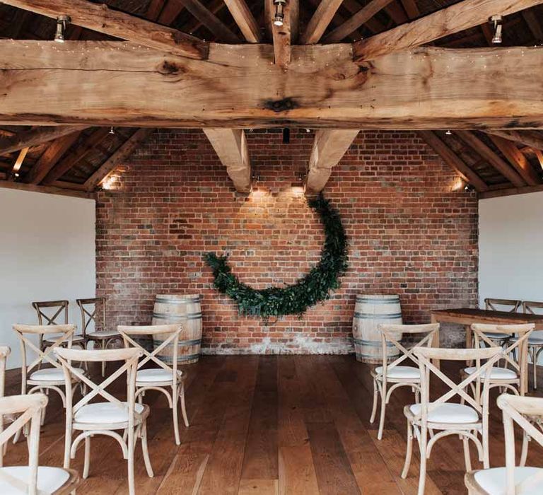 Ceremony room of Brickhouse Vineyard Devon wedding venue with foliage crescent moon and rustic light wooden chairs 