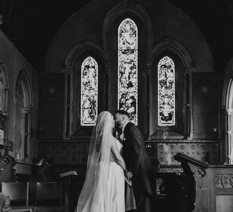 The bride and groom share their first kiss as a married couple at their traditional church wedding 