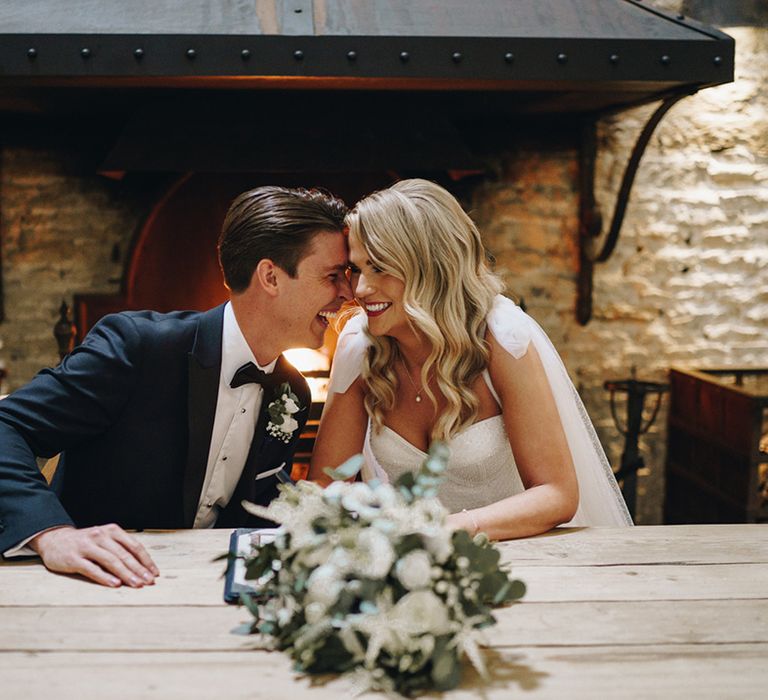 The bride and groom laugh together as they sit at the registry table 