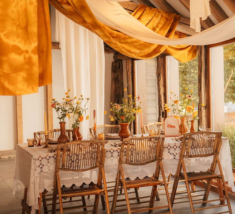 Woodstock wedding inspiration with orange and white wedding drapery surrounded by orange and yellow wedding flowers 