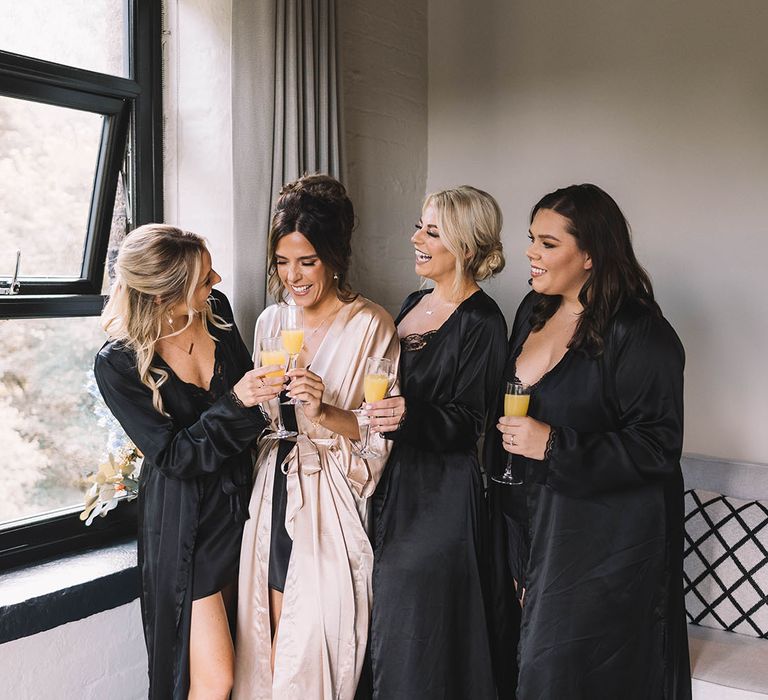 The bridesmaids wearing black satin robes 