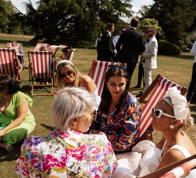 Summer wedding with guests sitting on deck chairs on the lawn 