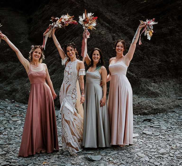 Bridal party wearing mismatched bridesmaid dresses in satin material for the coastal wedding 