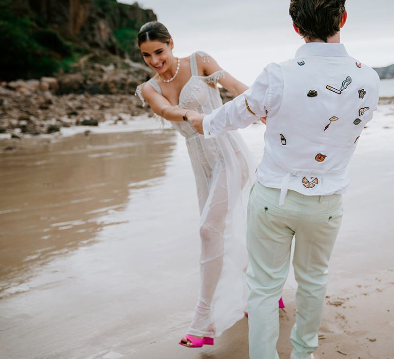 Bride and groom dance together on the beach together at their coastal wedding 