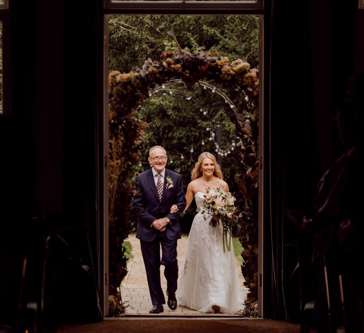 Bride enters the wedding ceremony at Larmer Tree Gardens